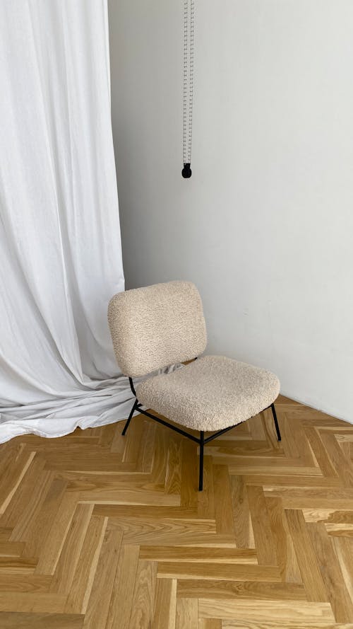 A Chair on a Wooden Floor Near a White Wall