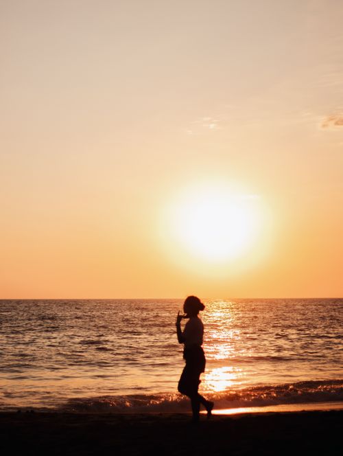 Free A solitary figure silhouetted against a stunning sunset on Acapulco beach. Stock Photo