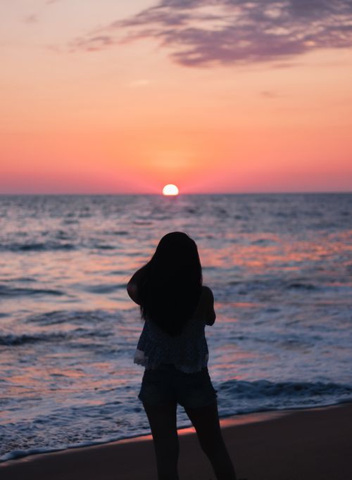 Free Silhouette of a woman enjoying a vibrant sunset at Acapulco beach. Stock Photo