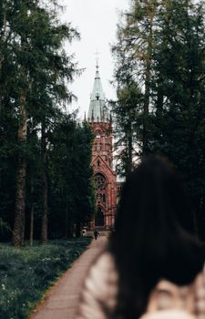 A serene Gothic church tower peeks through lush trees on a peaceful walkway in Karlsruhe, Germany.