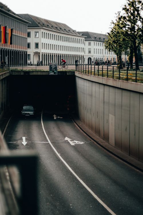 Free City scene in Karlsruhe featuring a tunnel underpass with cars and bikes, showcasing urban architecture. Stock Photo