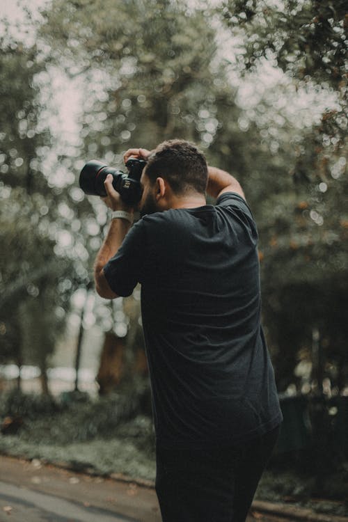 Man in Black Shirt Taking Photo with a Camera