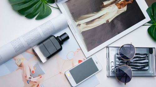 Free Flat lay of fashion items including sunglasses, perfume, and a magazine on a white surface. Stock Photo