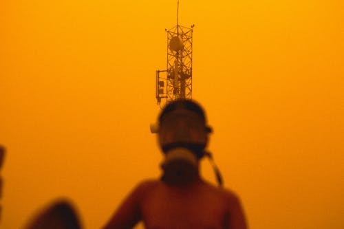 A Person in a Gas Mask and a Radio Tower in the Background