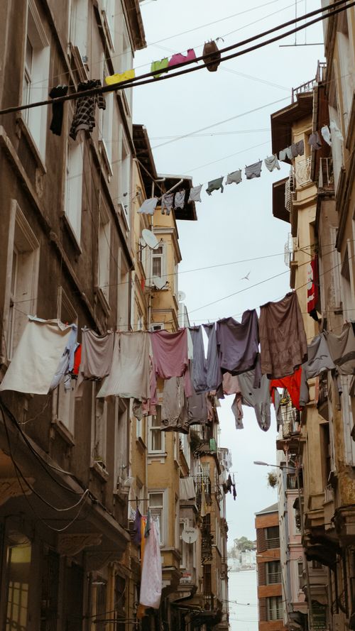 Free Colorful clothes hang on lines between old buildings in a narrow Istanbul alley. Stock Photo