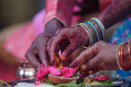 Free Colorful Indian wedding ritual featuring henna-decorated hands performing a traditional ceremony with flowers. Stock Photo