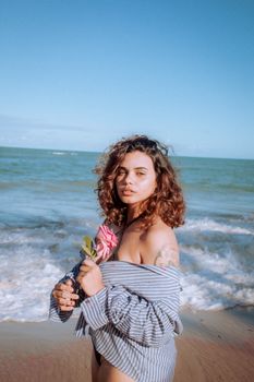 Portrait of a woman with flowers at the beach, showcasing a serene seaside moment.