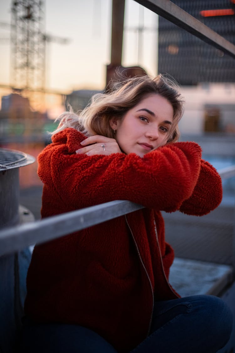 Woman In Red Fleece Sweater Leaning On The Gray Metal Railings