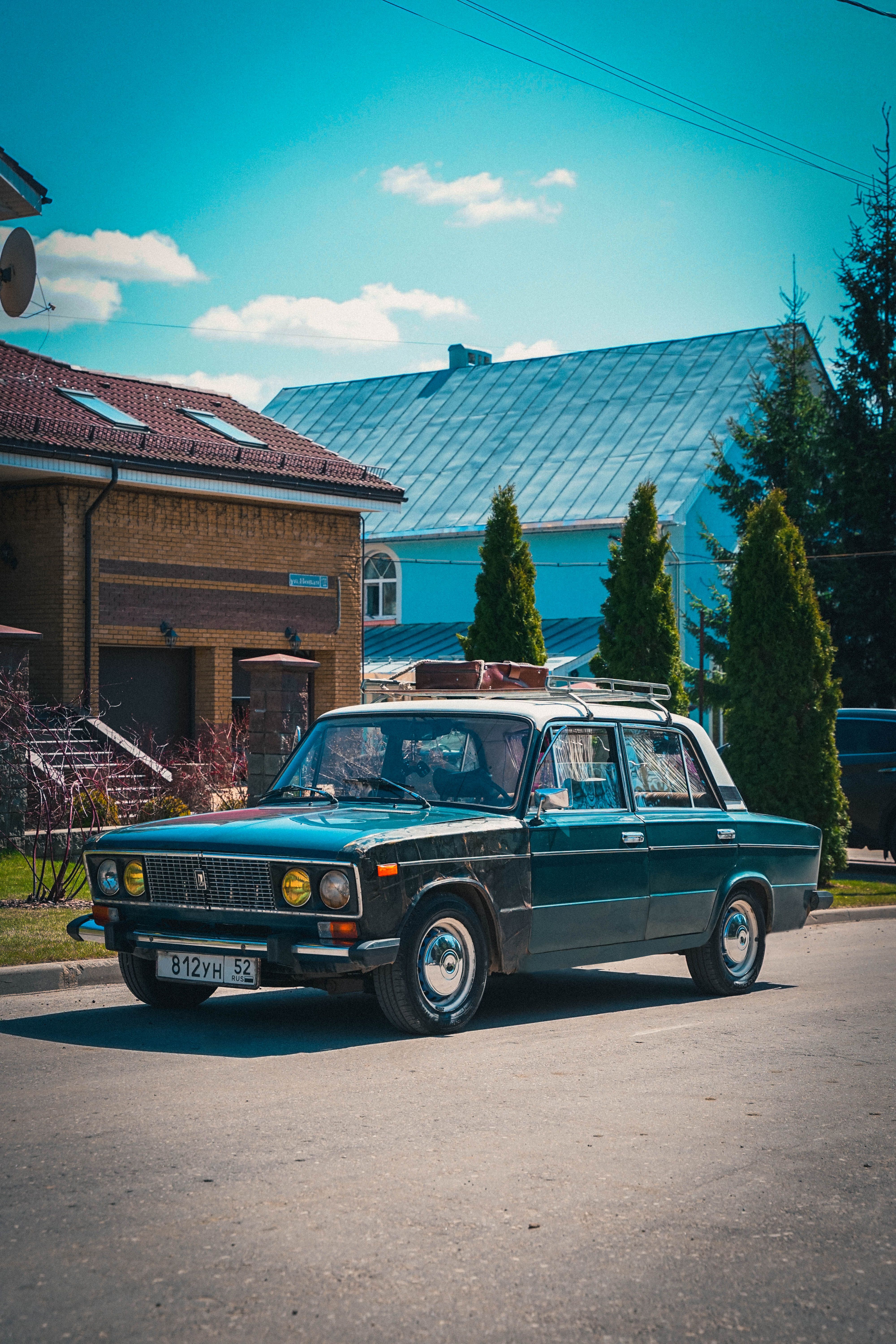 Classic vintage car parked on a sunny street in a suburban neighborhood.