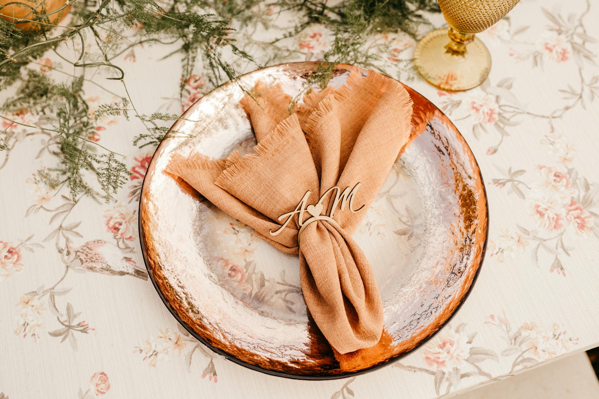 Close-up of a floral table setting with a monogrammed napkin on a decorative plate, creating an elegant dining atmosphere.