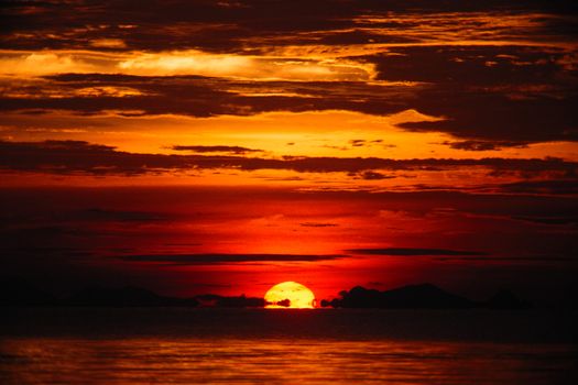 Stunning sunset with fiery orange skies over a calm ocean, perfect for tranquil scenes.