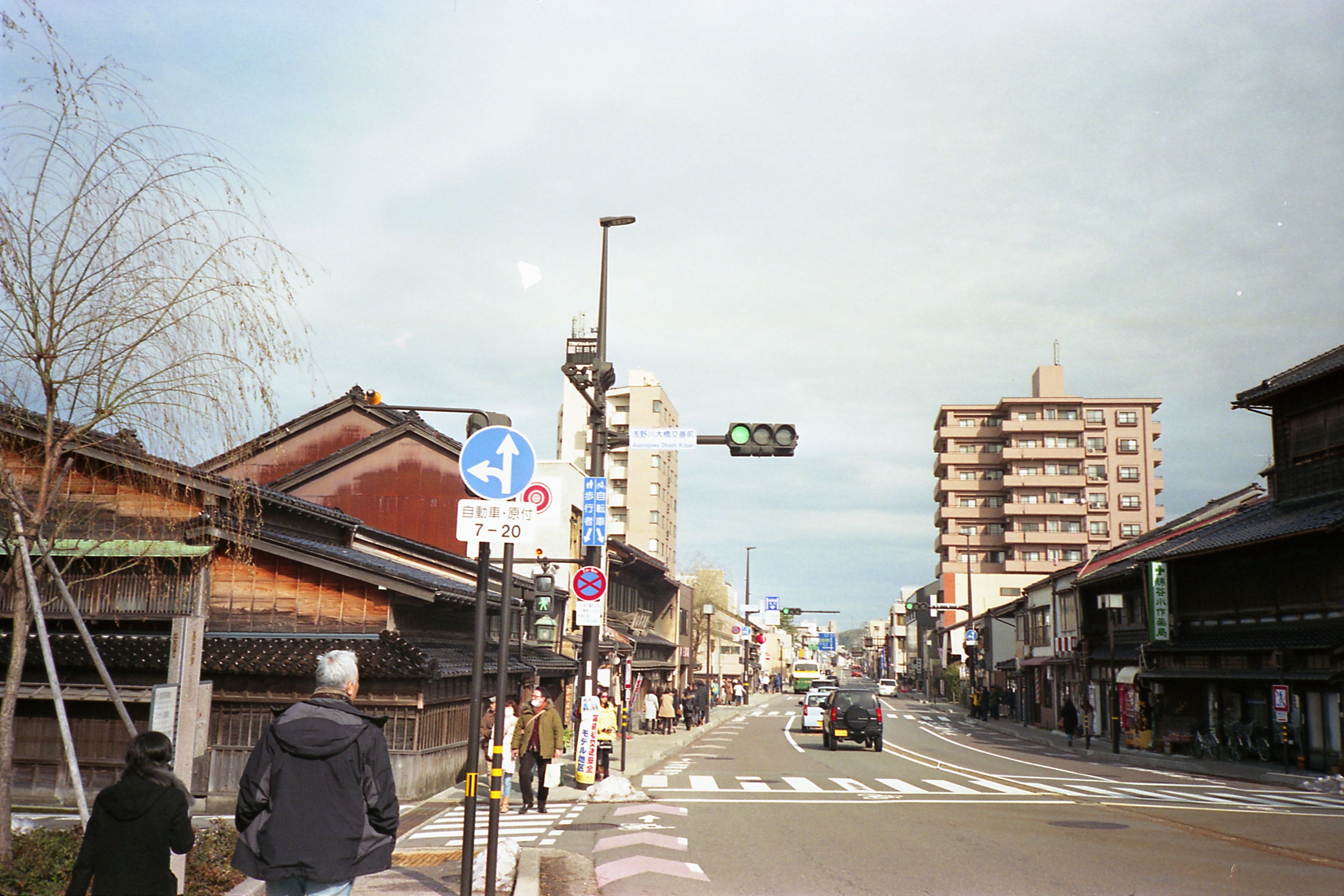 Street view of Kanazawa showcasing traditional and modern architecture with pedestrians and traffic.
