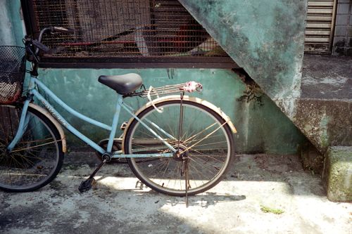 Free A vintage blue bicycle rests against a textured urban wall, evoking nostalgia and simplicity. Stock Photo