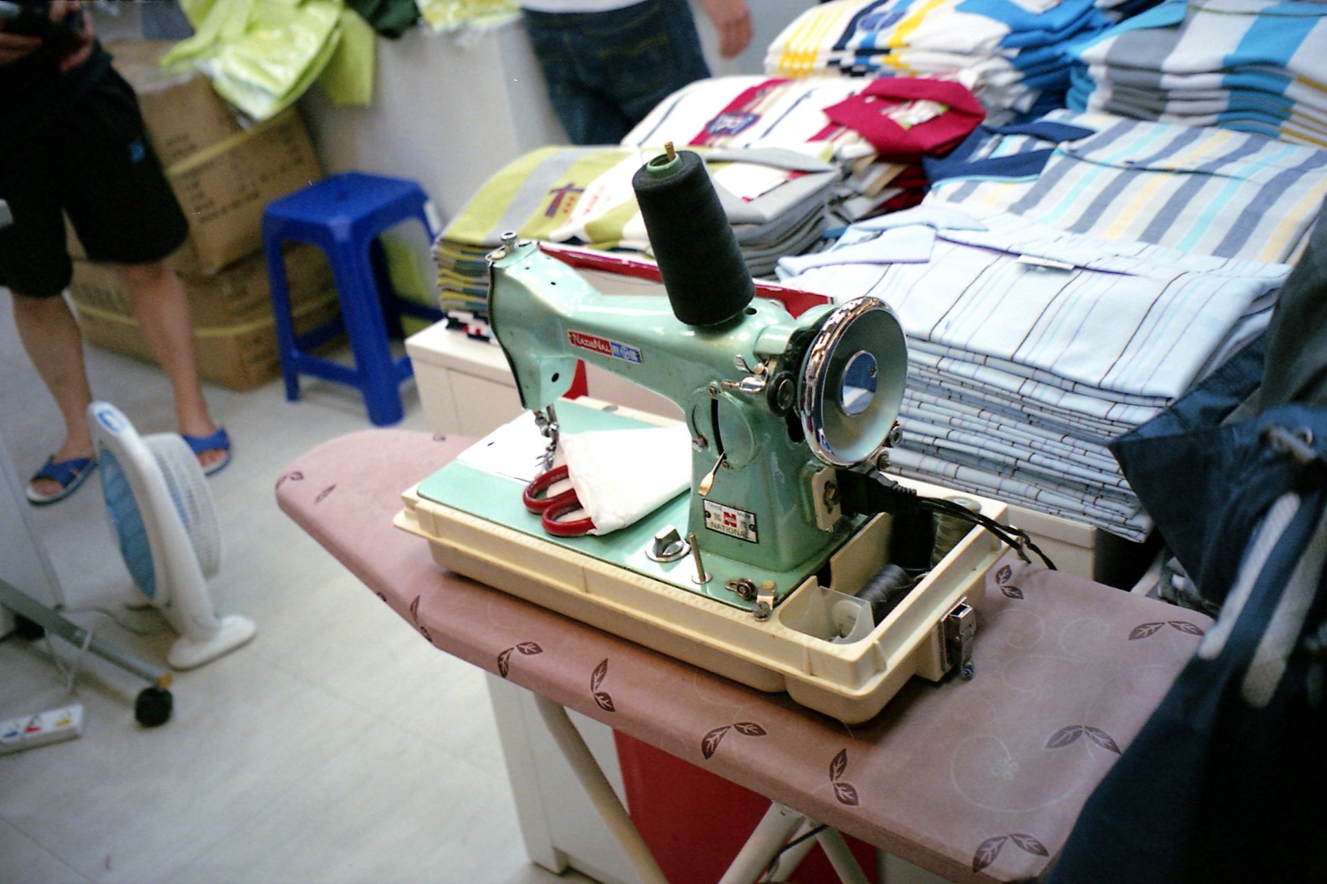 A vintage sewing station with clothes and fabrics in a tailor's workspace.