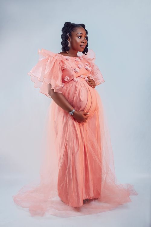 Free Beautiful maternity photo of a stylish woman in a peach dress, showcasing elegance and grace. Stock Photo