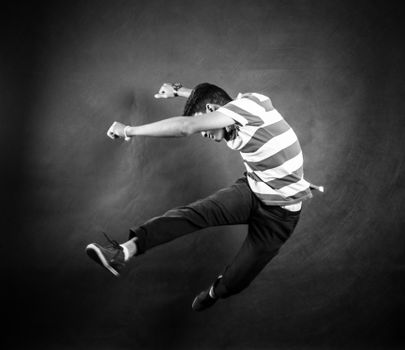 Black and white photo of a man in mid-air jump, showcasing energy and style.