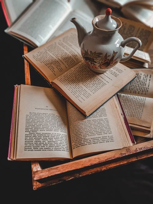 Free A cozy scene of open books and a kettle on a wooden table, ideal for study and relaxation. Stock Photo