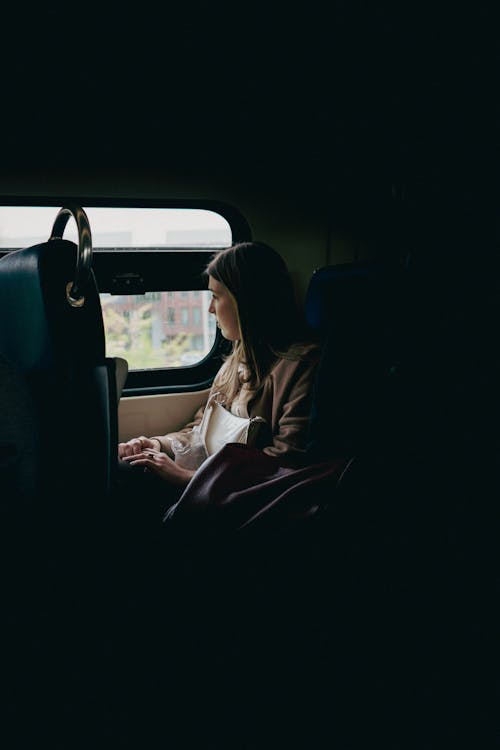 A Woman Sitting on a Chair and Looking Through the Window