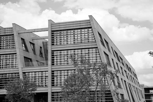 A Grayscale Photo of a Concrete Building Under the Cloudy Sky