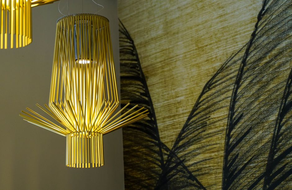 An elegant yellow bamboo chandelier illuminates a creative interior space with artistic design and warm ambiance.
