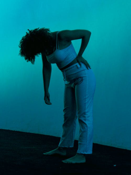 Woman in White Tank Top Standing with Her Head Down