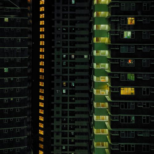 Free A night-time view of brightly illuminated high-rise apartment buildings creating a striking cityscape. Stock Photo