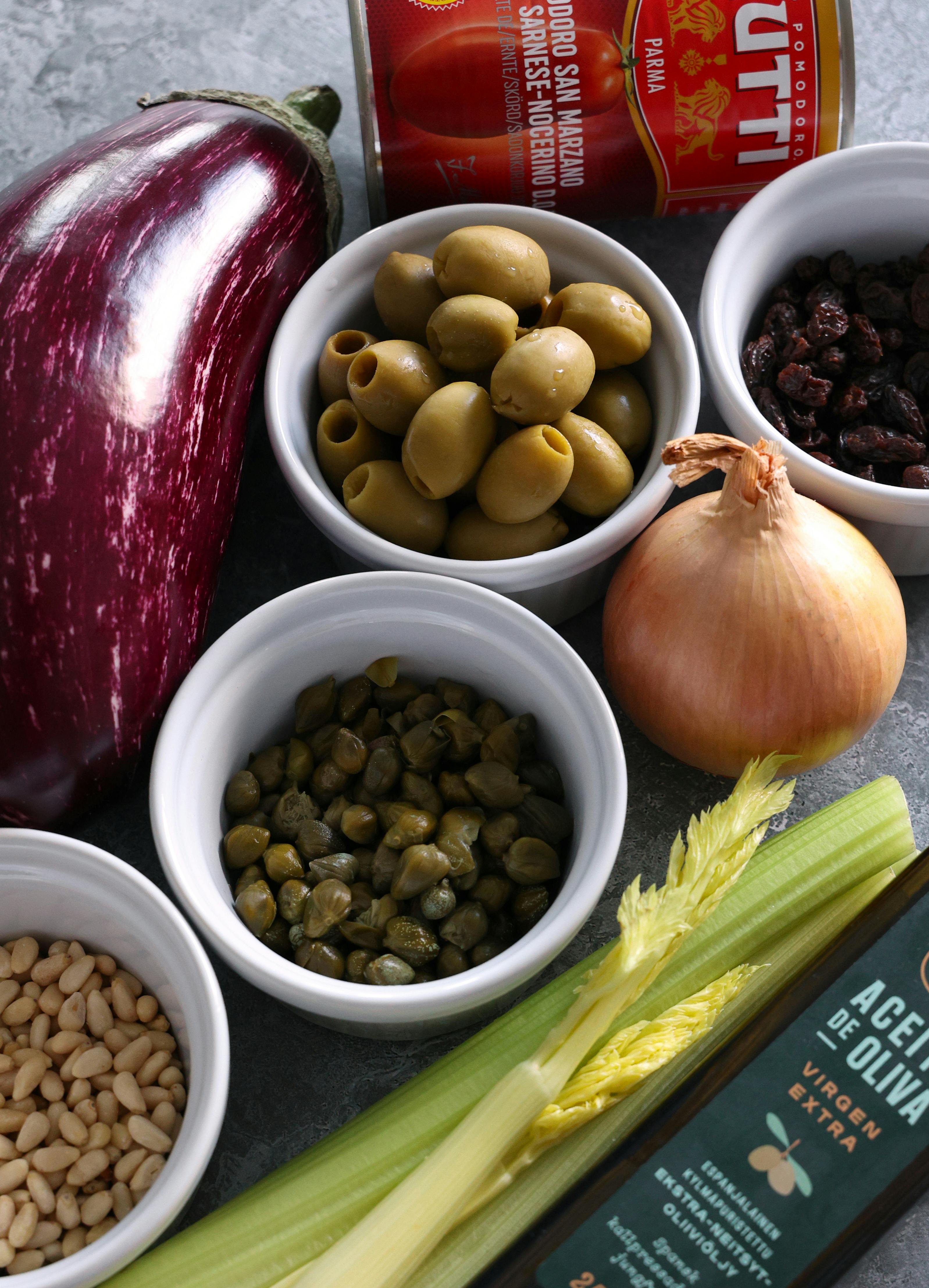 A vibrant selection of fresh Mediterranean ingredients for cooking, featuring eggplant, olives, and olive oil.