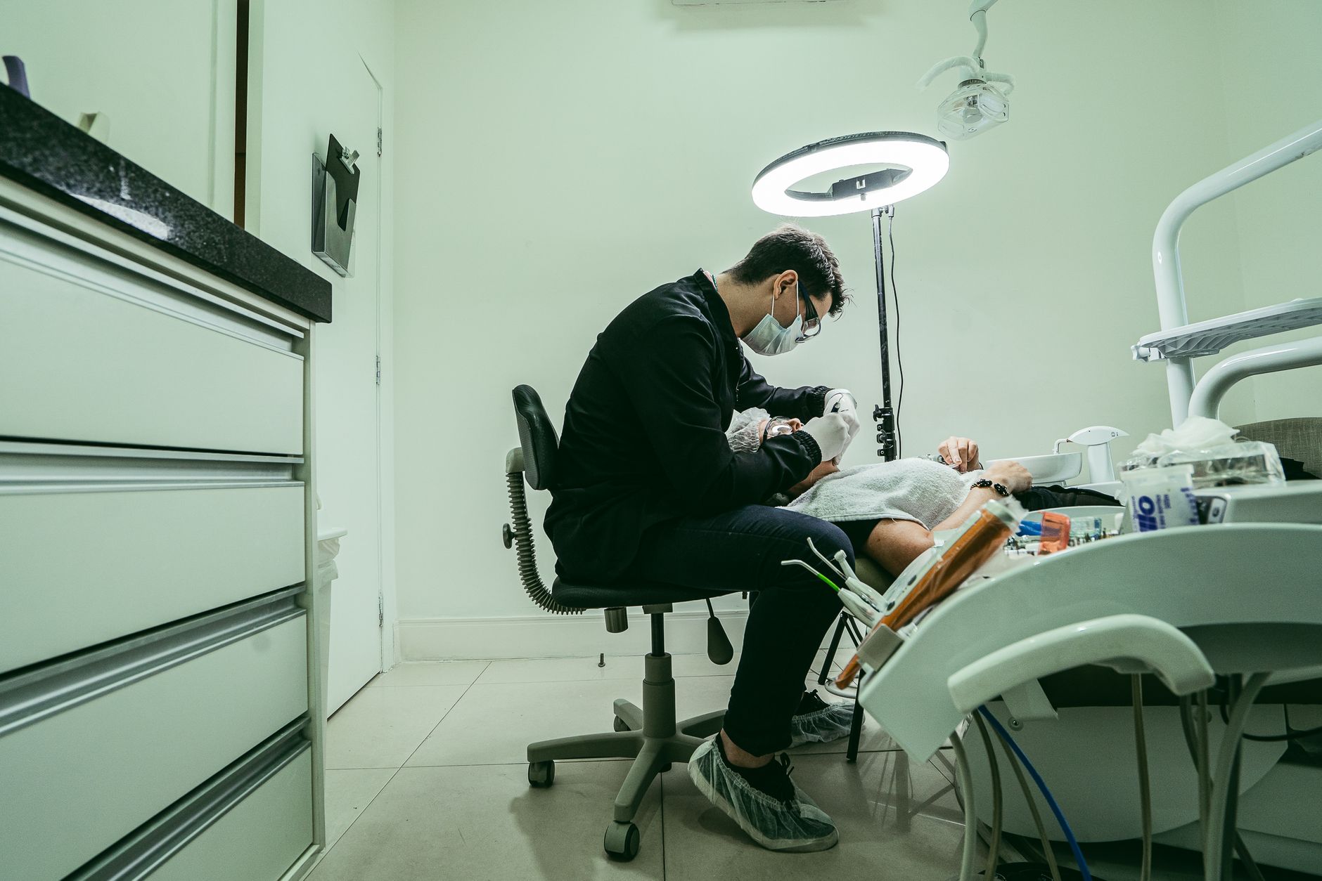 A dentist wearing a mask treats a patient in a modern dental clinic in Brazil.