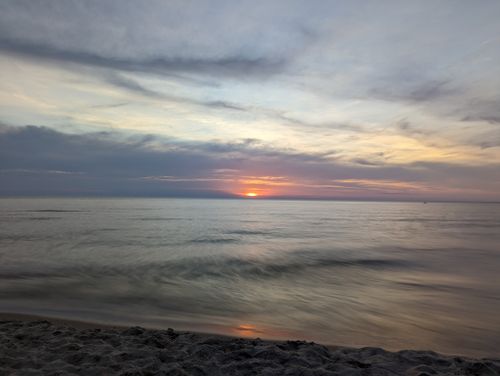 Free Peaceful beach view with a captivating sunset over calm ocean waters, perfect for relaxation themes. Stock Photo