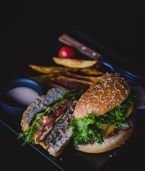 Free Burger With Green Leafy Vegetable and Cheese on Black Plate Stock Photo