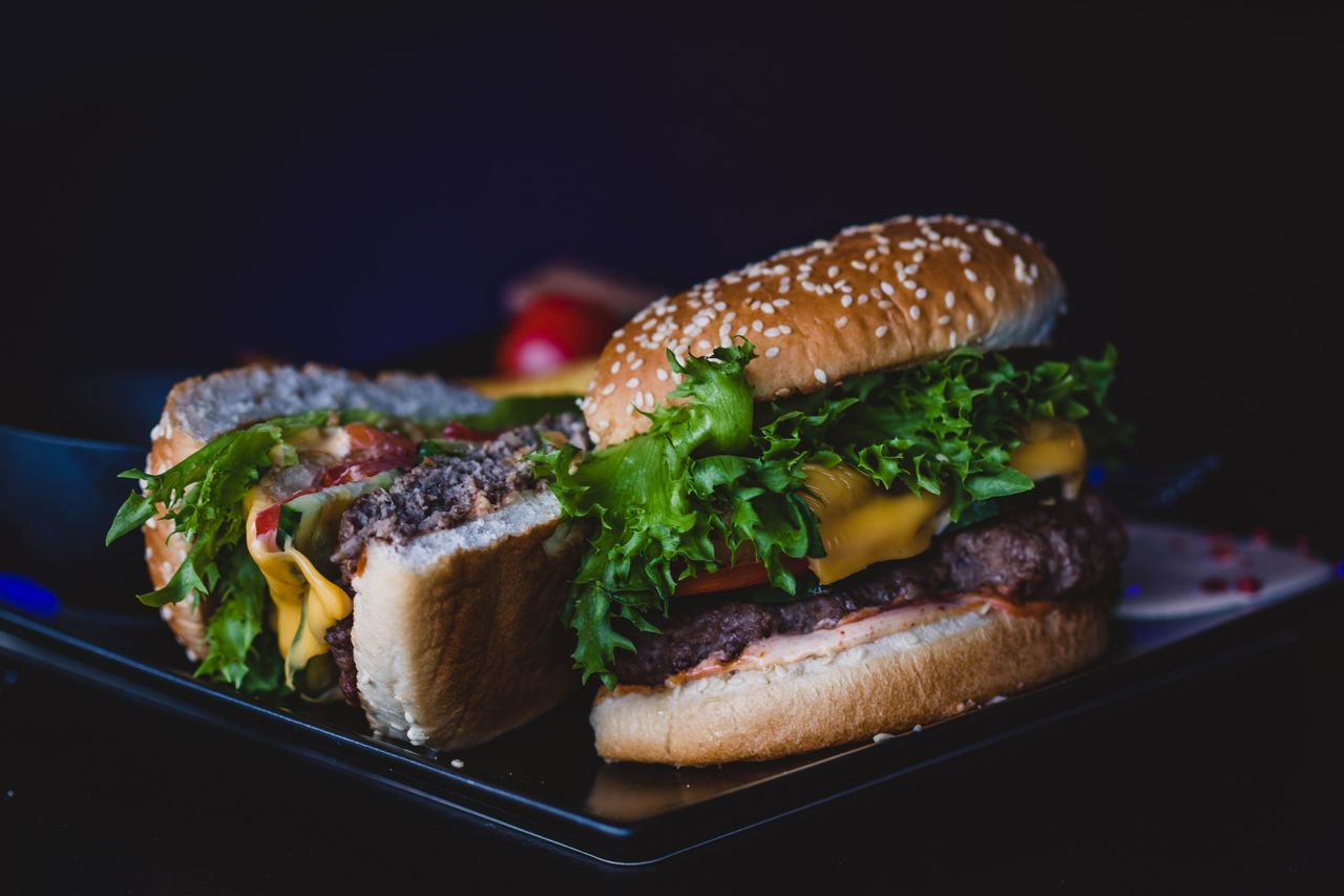 delicious cheeseburger with lettuce and tomato served on a dark plate