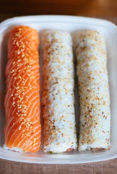 Delicious salmon sushi rolls topped with sesame seeds, perfect for lunch or dinner.