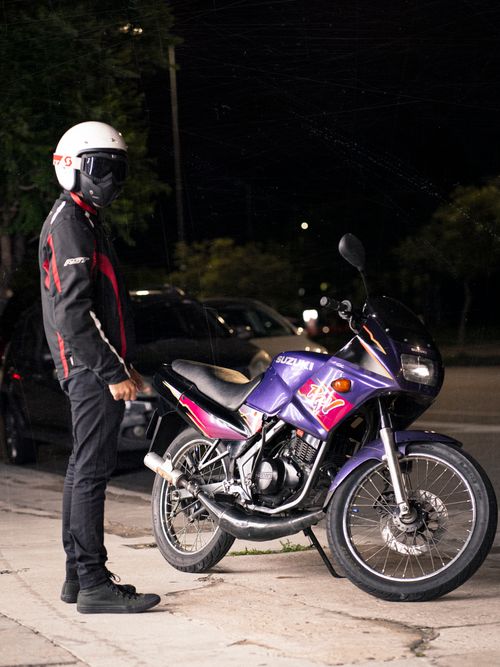 Free A man in a helmet stands beside a sports bike on a city street at night. Stock Photo