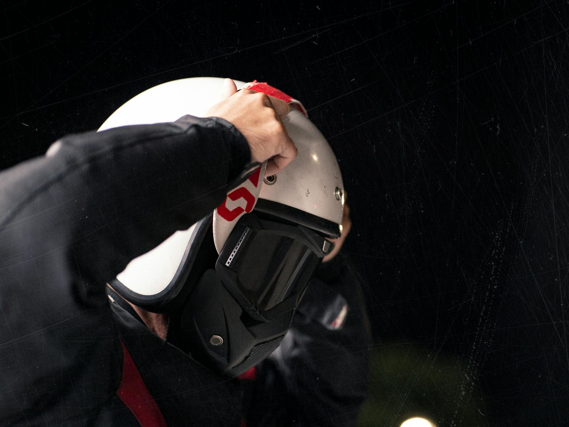 Detailed close-up of a person putting on a motorcycle helmet with goggles, emphasizing safety and protection.