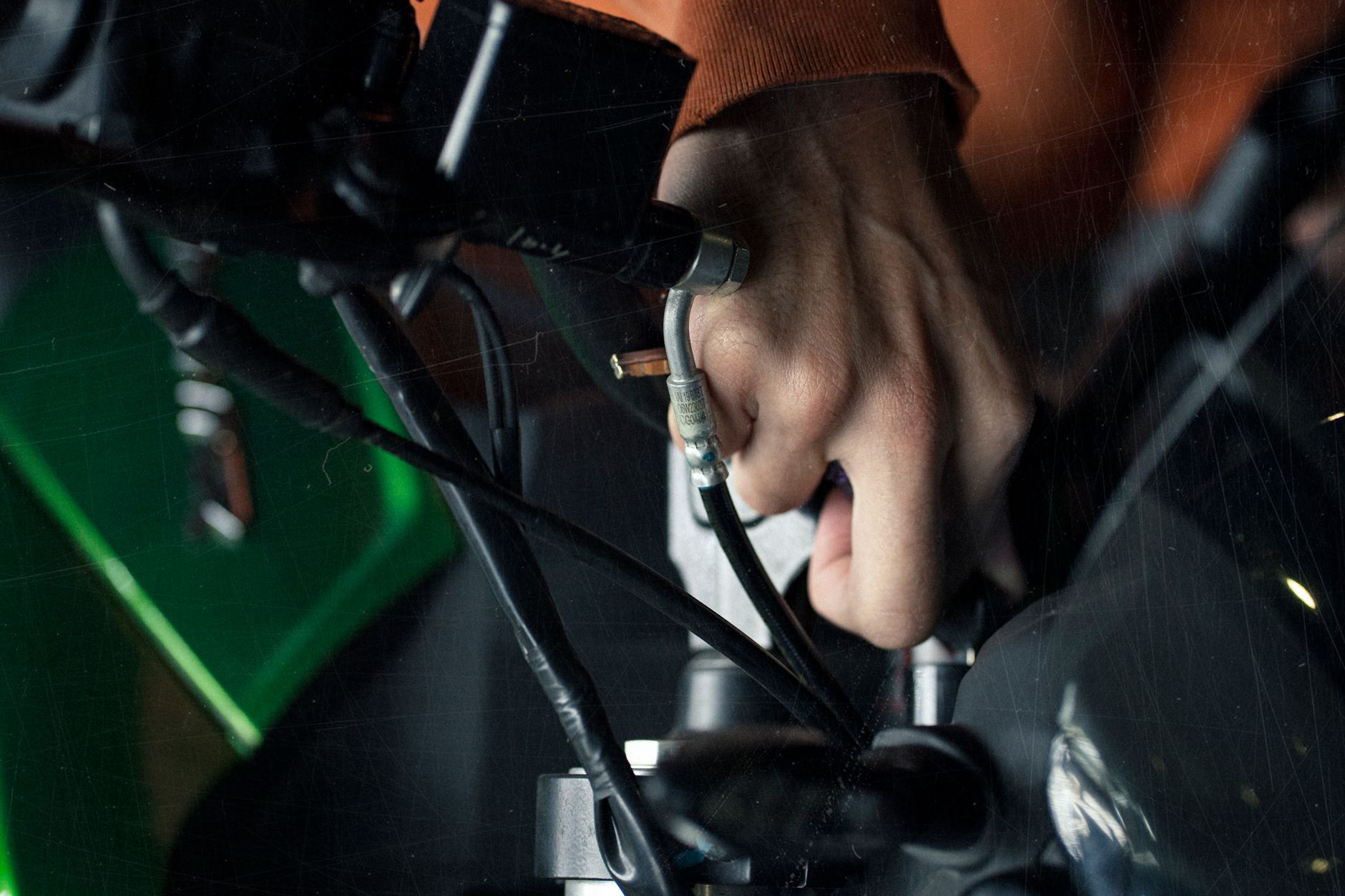 A detailed close-up of a hand adjusting motorcycle cables, showcasing technical maintenance.