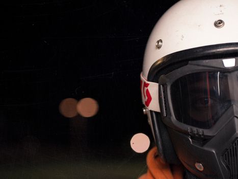 A close-up view of a motorcyclist's helmet at night, showcasing safety gear and details.