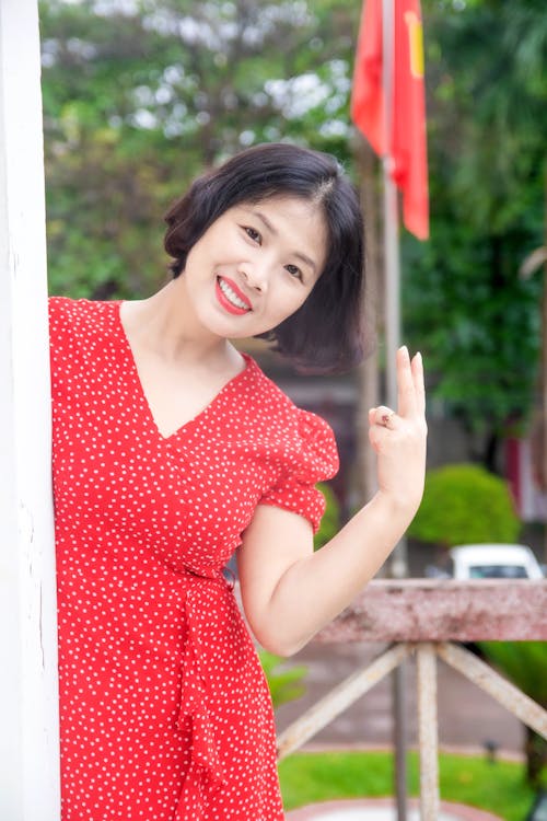 Woman in Red and White Polka Dot Dress Doing Peace Hand Sign