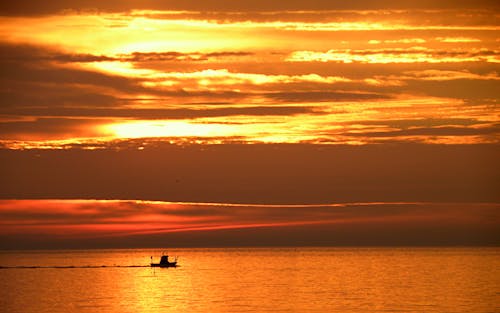Free Silhouette of a Boat on Water at Sunset Stock Photo