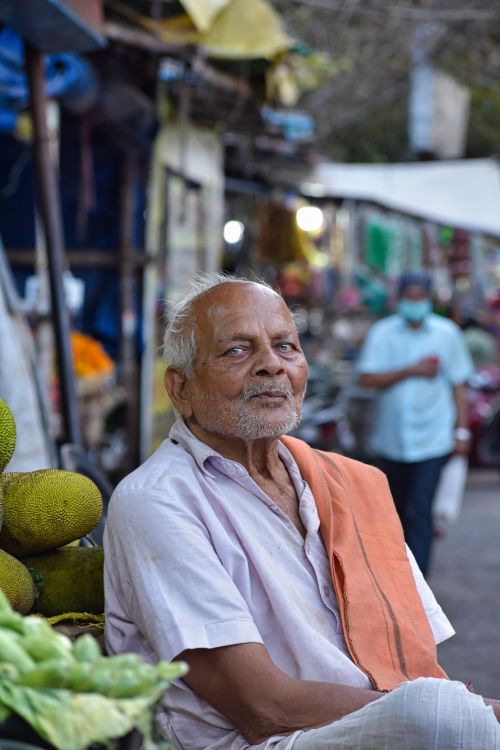 Free A senior man sitting at a bustling street market in Bhubaneswar, India. Stock Photo