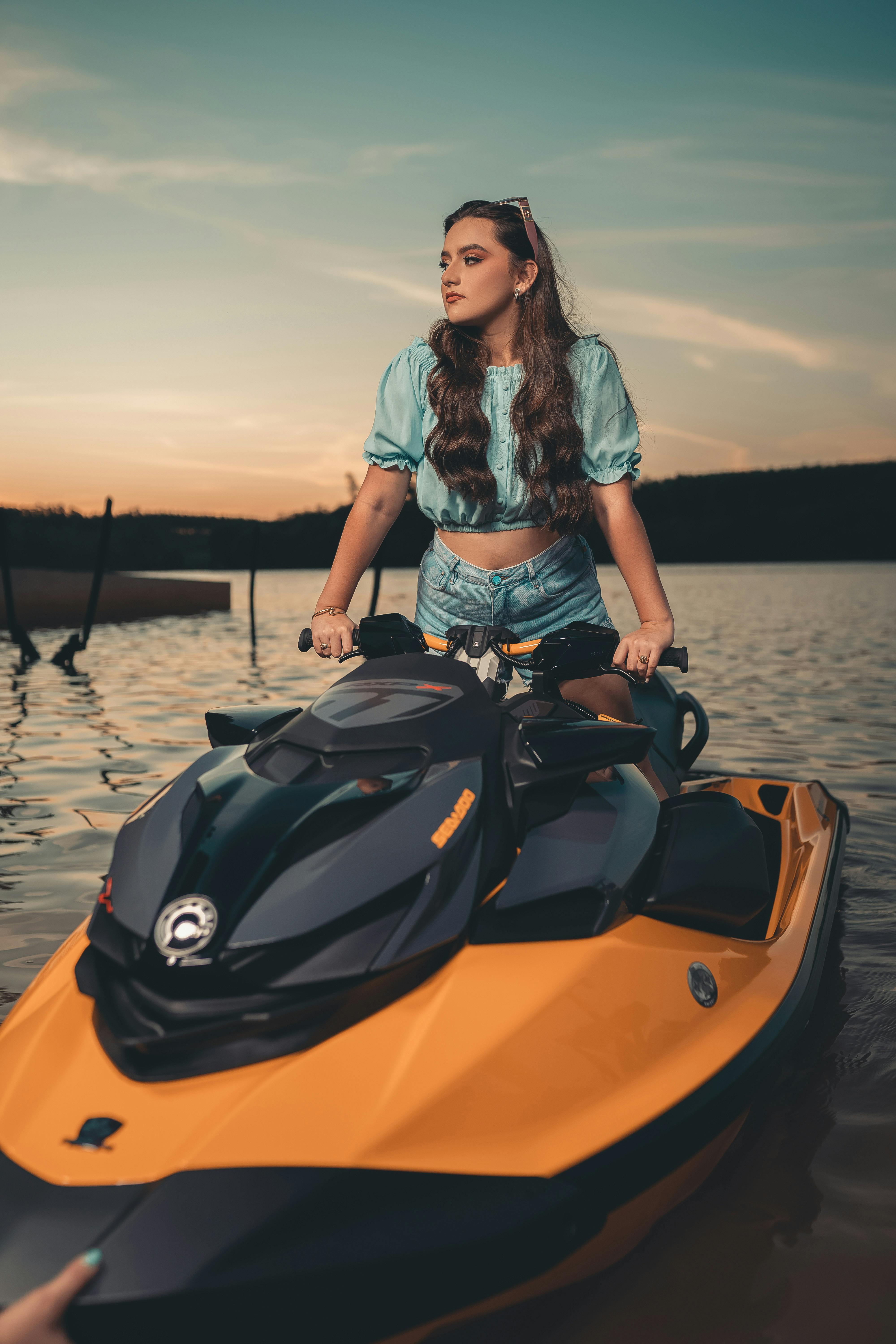 a woman in blue crop top riding yellow jet ski