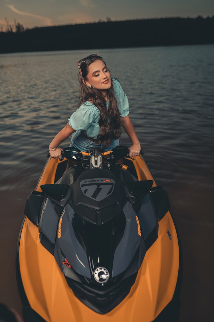 A Woman In Blue Shirt Riding A Jetski With Her Eyes Closed