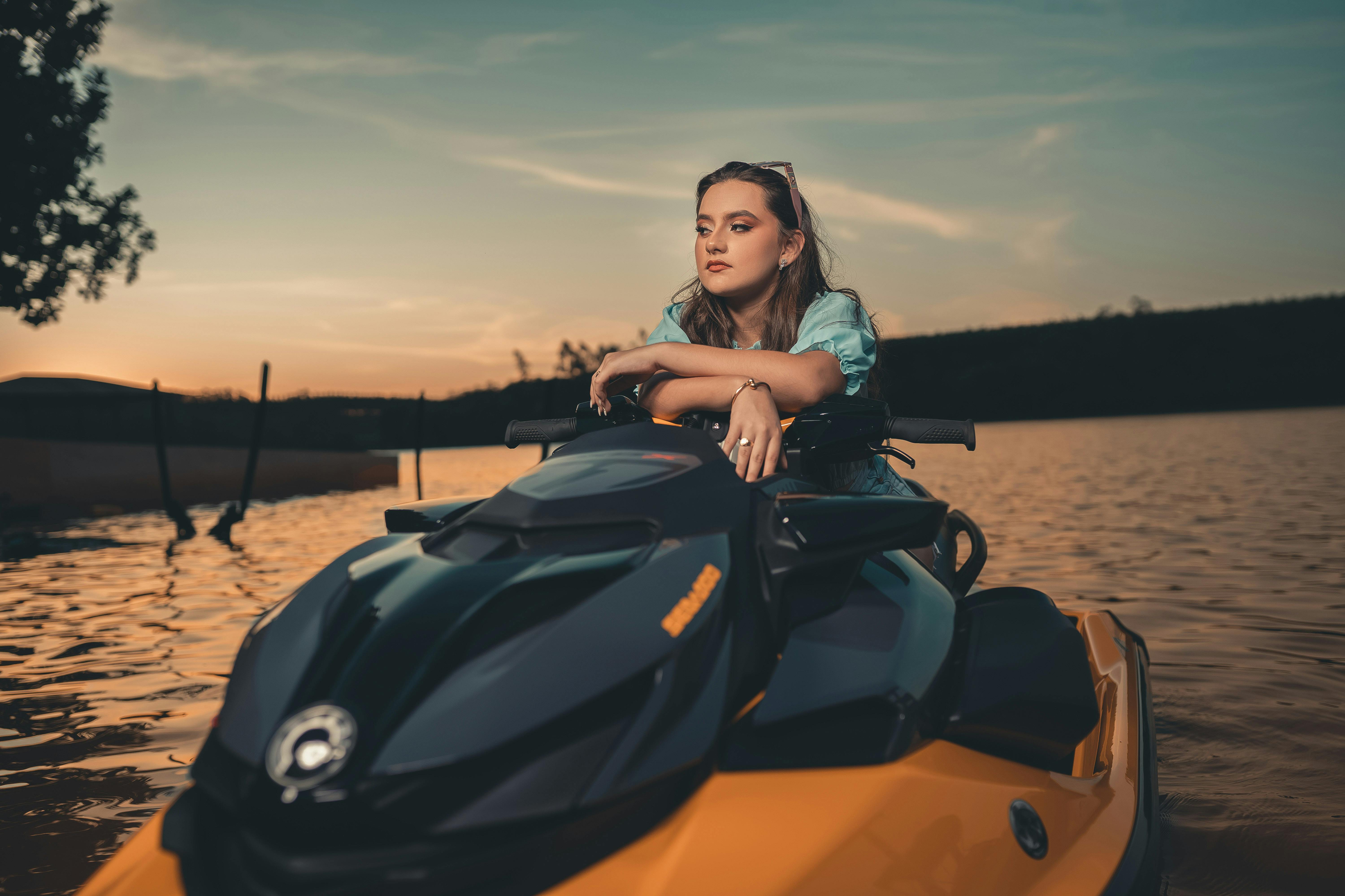 a woman sitting on orange and black jet ski