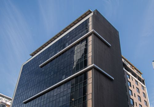 Free Low angle view of a contemporary skyscraper with glass windows against a clear blue sky. Stock Photo