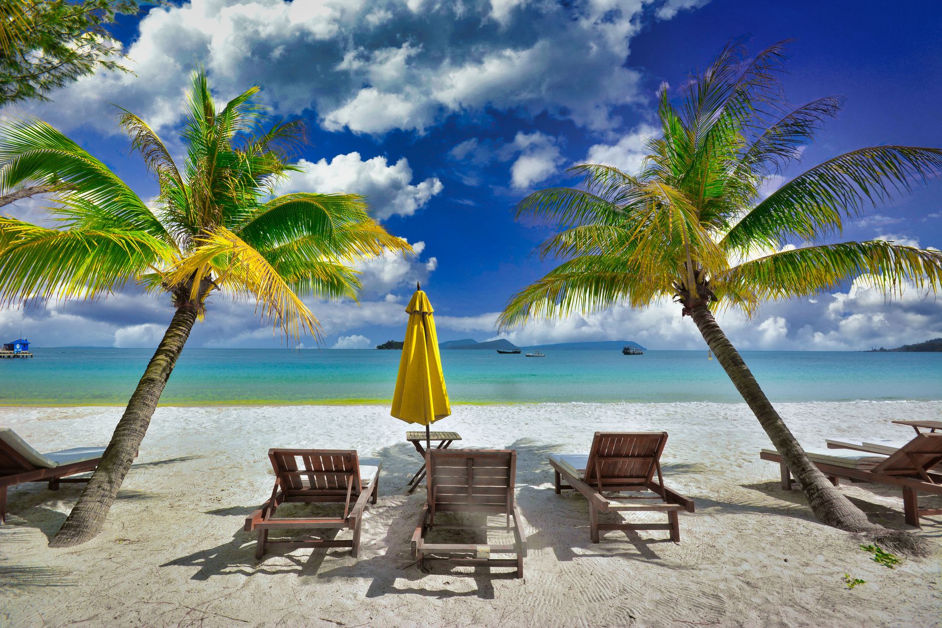 Peaceful tropical beach with palm trees and lounge chairs in Koh Rong, Cambodia.