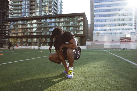 Athlete preparing for training on a sunny urban soccer field.