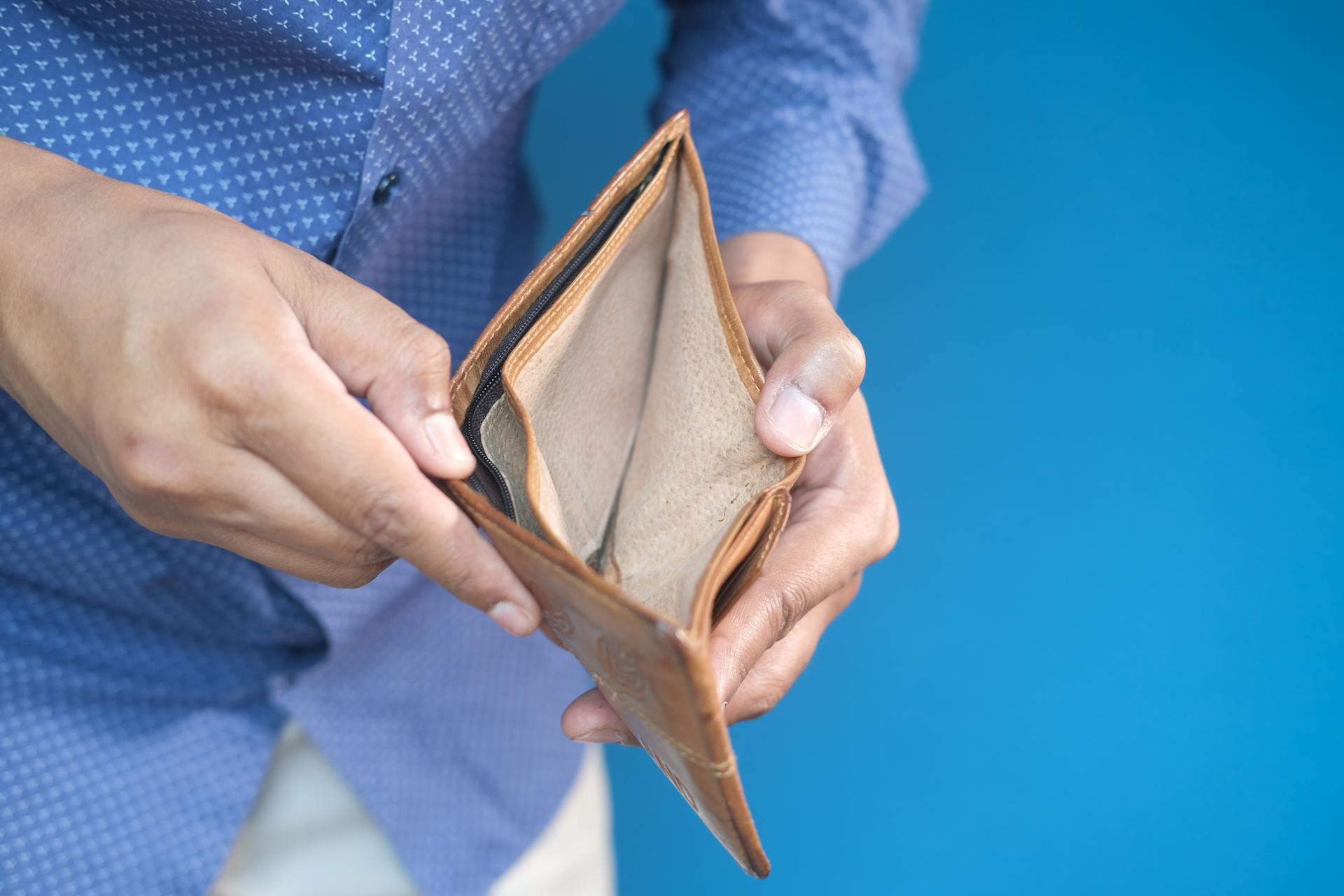 Close-up of hands holding an empty wallet, symbolizing financial challenges.