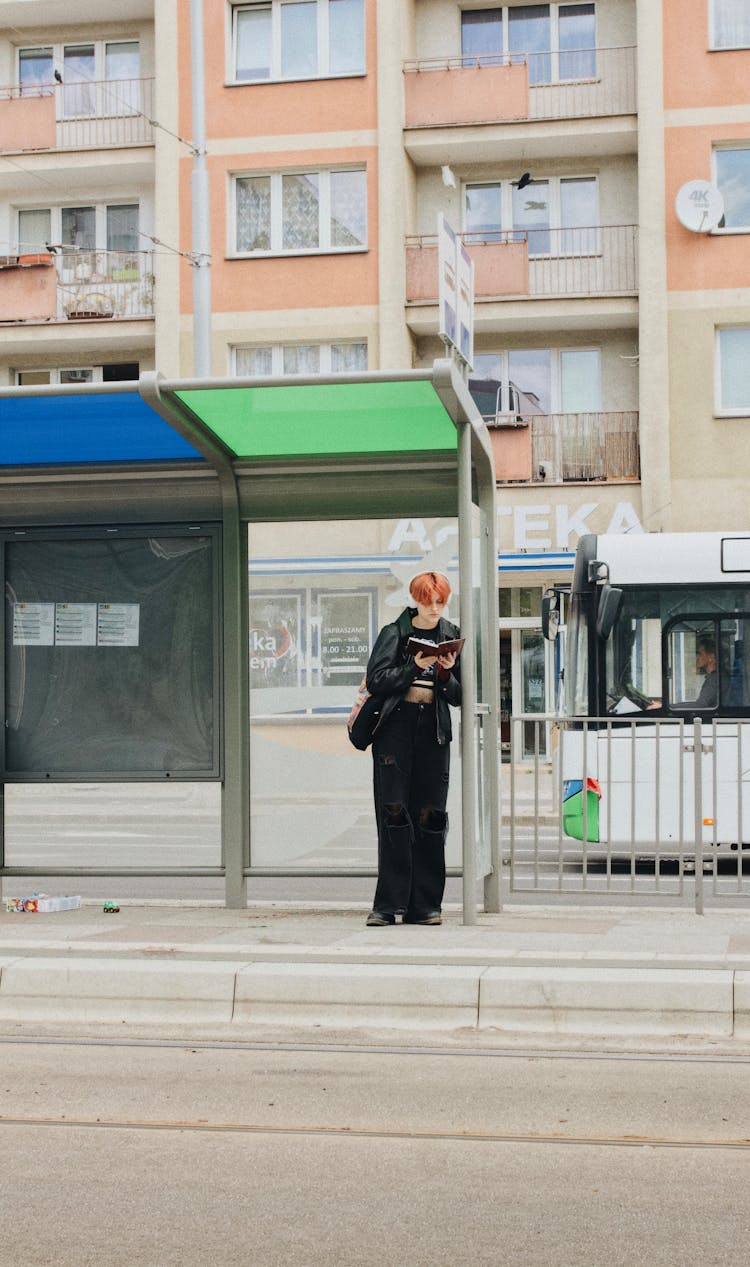 A Man Reading A Book While Standing On The Street