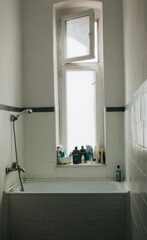 Elegant vintage-style bathroom with a tall window above the bathtub, offering a serene and cozy vibe.