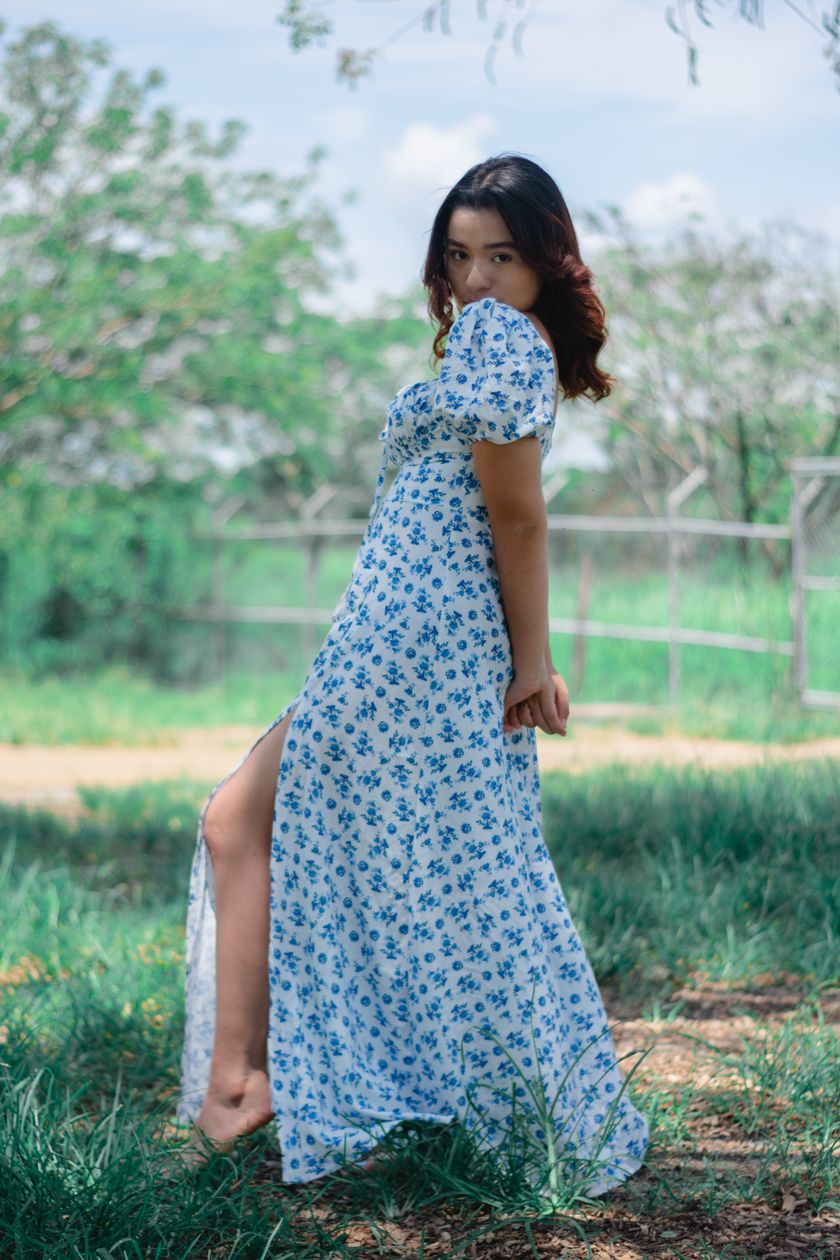 A blue floral day dress worn standing outdoors, full skirt and sleeve in frame
