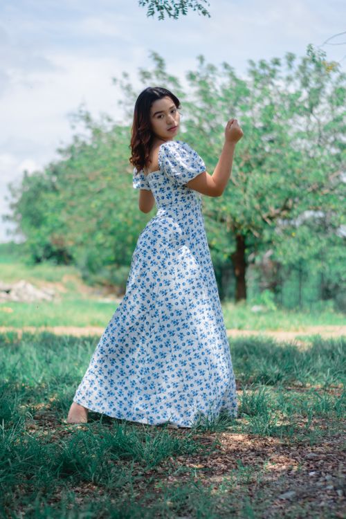 Free A young woman in a floral dress posing outdoors on a sunny day. Stock Photo